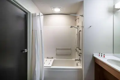 a bathroom with a shower and a tub and a sink at Microtel Inn & Suites by Wyndham Carlisle in Carlisle
