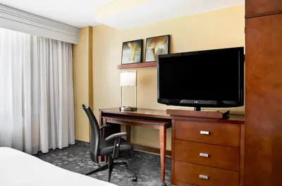 a hotel room with a desk with a television and a bed at Courtyard by Marriott Newark Downtown in Newark