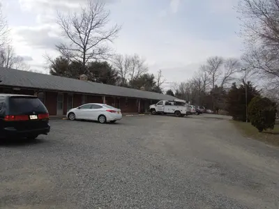 a parking lot with two cars parked in front of a building at Slumberland Motel Mount Holly in Mount Holly