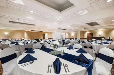a large banquet hall with white tables and chairs at Best Western Grand Victorian Inn in Sayre