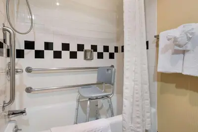 a bathroom with a shower and a chair in it at Best Western Grand Victorian Inn in Sayre
