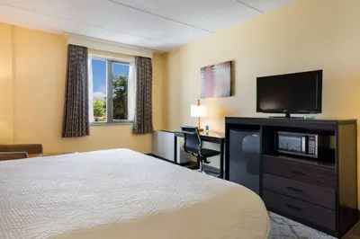 a hotel room with a bed and a flat screen tv at Best Western Grand Victorian Inn in Sayre