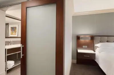a bedroom with a bed and a sink and a mirror at Hilton Philadelphia City Avenue in Philadelphia