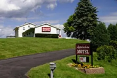 a house on a hill with a sign on the side of a road at Appalachian Motel in Vernon