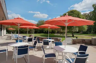 a group of tables and chairs with red umbrellas at Holiday Inn Express Princeton Southeast by IHG in Plainsboro