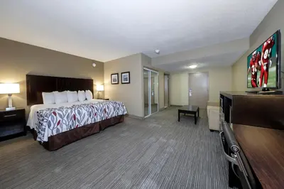 a hotel room with a bed and a flat screen tv at Red Roof Inn & Suites Newburgh - Stewart Airport West Point in New Windsor