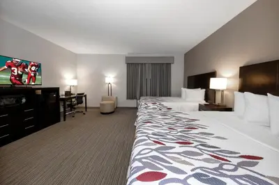 a hotel room with two beds and a flat screen tv at Red Roof Inn & Suites Newburgh - Stewart Airport West Point in New Windsor