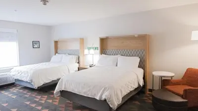 a hotel room with two beds and a chair at Holiday Inn & Suites Philadelphia W - Drexel Hill by IHG in Drexel Hill