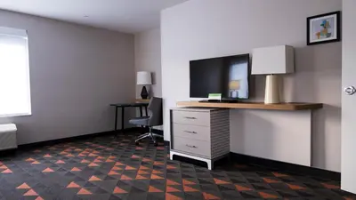 a hotel room with a desk with a tv and a chair at Holiday Inn & Suites Philadelphia W - Drexel Hill by IHG in Drexel Hill