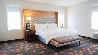 a bedroom with a large white bed and a stool at Holiday Inn & Suites Philadelphia W - Drexel Hill by IHG in Drexel Hill
