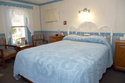 a bedroom with a large bed with a blue comforter at Myer Country Motel in Milford