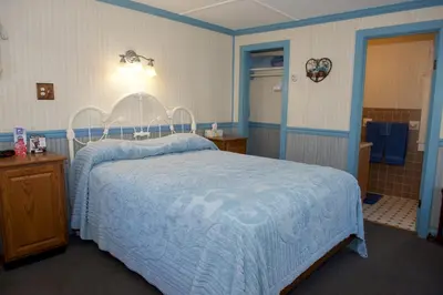 a blue bedroom with a bed and a bathroom at Myer Country Motel in Milford