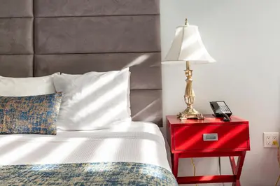 a bed with a red night stand with a lamp on it at Hotel St. James in New York