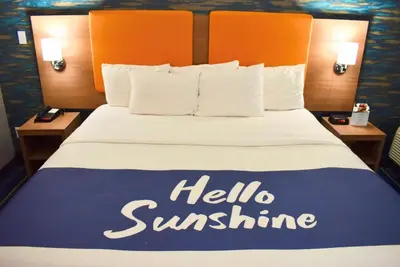 a hotel bed with a hello sunshine sign on it at Days Inn by Wyndham Wayne in Wayne