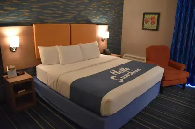 a hotel room with a large bed and a chair at Days Inn by Wyndham Wayne in Wayne