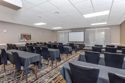 a conference room with tables and chairs and a screen at La Quinta by Wyndham Clifton/Rutherford in Clifton