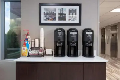 a counter with four coffee machines on top of it at La Quinta by Wyndham Clifton/Rutherford in Clifton