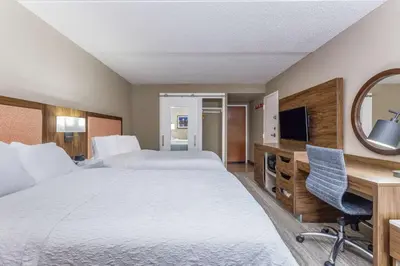 a hotel room with two beds and a desk and a television at Hampton Inn Harrisburg-East/Hershey in Harrisburg