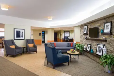 a lobby with a couch and chairs and a tv at Larkspur Landing Carlisle in Carlisle