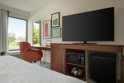 a bedroom with a television and a desk with a chair at Hampton Inn Lancaster in Lancaster
