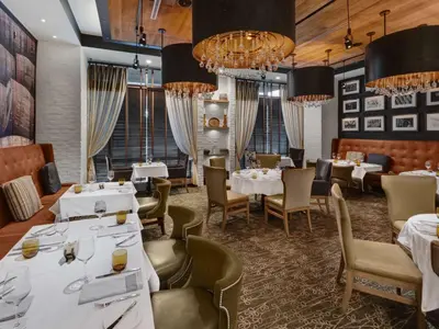 a restaurant with white tables and chairs and chandeliers at Hilton Harrisburg near Hershey Park in Harrisburg