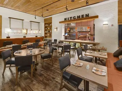 a restaurant with tables and chairs and a kitchen at Hilton Harrisburg near Hershey Park in Harrisburg
