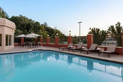 a swimming pool with lounge chairs and tables on a balcony at Hilton Garden Inn Harrisburg East in Harrisburg