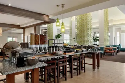 a restaurant with a buffet line with tables and chairs at Hilton Garden Inn Harrisburg East in Harrisburg