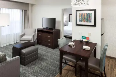 a hotel room with a table and a room with a bed at Homewood Suites by Hilton Mahwah in Mahwah
