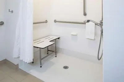 a bathroom with a shower with a table and a sink at Hampton Inn Limerick in Limerick