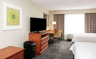 a hotel room with a bed and a desk with a television at Hampton Inn Parsippany in Parsippany