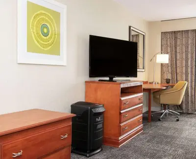 a hotel room with a desk and a flat screen tv at Hampton Inn Parsippany in Parsippany
