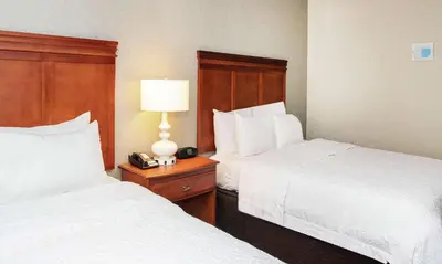 a hotel room with two beds and a lamp on a night stand at Hampton Inn Parsippany in Parsippany