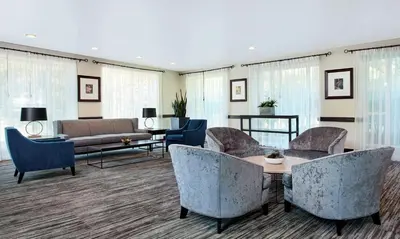 a living room with chairs and a couch and a table at Embassy Suites Parsippany in Parsippany