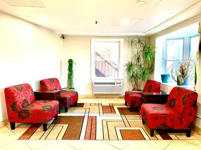 a waiting room with red chairs and a table and a window at Tappan Zee Hotel in West Nyack