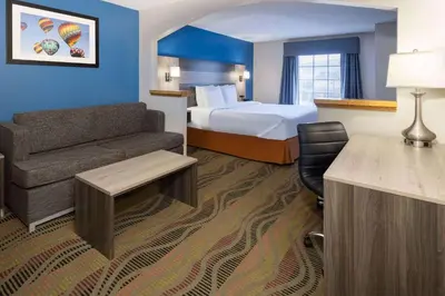 a hotel room with a bed and a couch at Baymont by Wyndham Budd Lake in Budd Lake