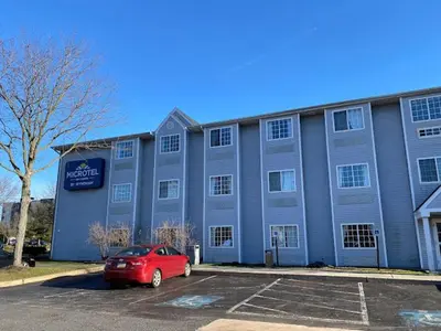 a red car parked in a parking lot in front of a building at Microtel Inn & Suites by Wyndham West Chester in West Chester