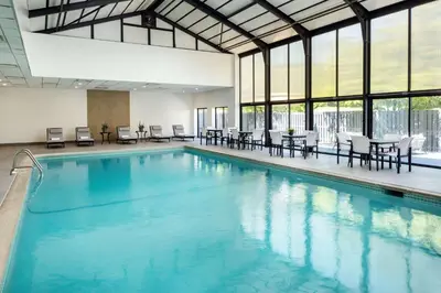 a large swimming pool with tables and chairs and windows at DoubleTree by Hilton Princeton in Princeton