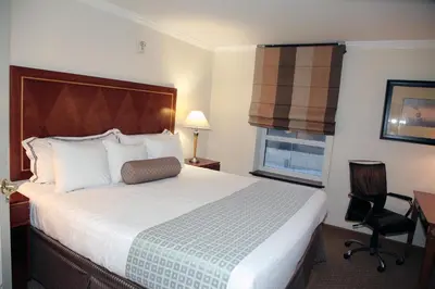 a hotel room with a large bed and a chair at Hotel Executive Suites in Carteret