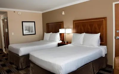 two beds in a hotel room with white pillows at Hotel Executive Suites in Carteret