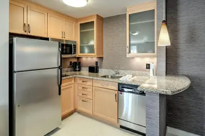 a kitchen with wooden cabinets and a stainless steel refrigerator at Residence Inn by Marriott Woodbridge Edison/Raritan Center in Woodbridge