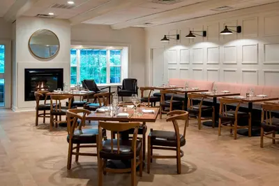 a dining room with tables and chairs and a fireplace at Delta Hotels by Marriott Basking Ridge in Basking Ridge