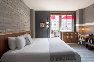 a bedroom with a large bed and a desk and a table at Hotel Henri NY in New York