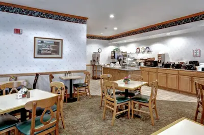 a restaurant with tables and chairs and a kitchen at Lancaster Inn & Suites in Manheim