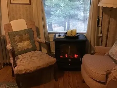 a living room with a fireplace and a chair at Brookview Manor Inn in Canadensis