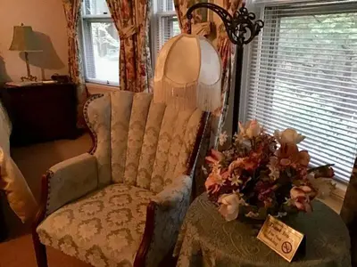 a living room with a chair and a table with flowers at Brookview Manor Inn in Canadensis