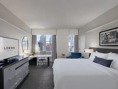 a hotel room with a large bed and a desk at Loews Philadelphia Hotel in Philadelphia