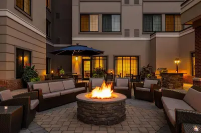 an outdoor patio with a fire pit with couches and an umbrella at Residence Inn by Marriott Williamsport in Williamsport