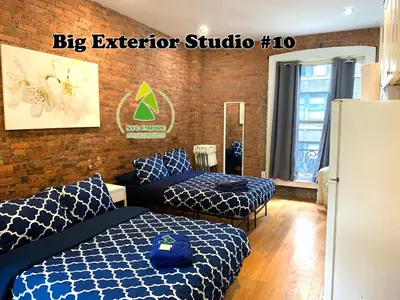 a bedroom with two beds and a brick wall at NYC Empire Apartments in New York