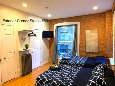 a bedroom with a bed and a brick wall at NYC Empire Apartments in New York